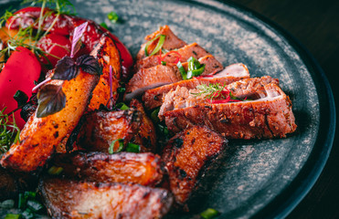 fried meat with potatoes, pepper, tomatoes, herbs and spices in plate