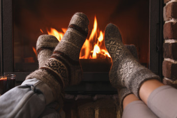 Couple resting near fireplace indoors, closeup. Winter vacation