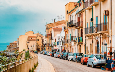 Cozy street with cars in Cefalu town Sicily reflex