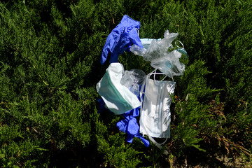 Group of masks and gloves lying on top of a bush. The waste from the covid19.