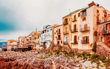 Fototapeta na wymiar Old houses on Rocky Coast at Cefalu Sicily reflex