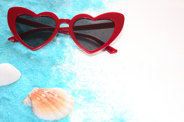 Sonnenbrille, Muscheln und blauer Sand