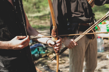 A man shoots a bow in the open air. The near foreshortening, two men. An arrow is pulled over the...