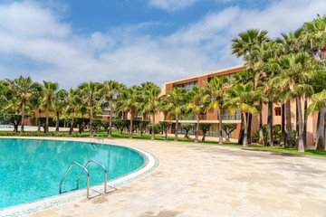Fototapeta na wymiar Modern luxurious pool with clean, clear, blue water, palm trees