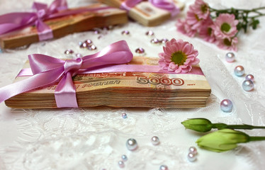 Packs of Russian banknotes and a bow with a gift ribbon, on a background of lace. Dowry and ransom of the bride, birthday present, cash prize.