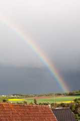 bright rainbow over rural landscape with dark sky