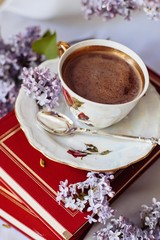 Obraz na płótnie Canvas Cup of coffee with lilac petals, Cup of coffee near bouquet of spring flowers. Morning inspiration
