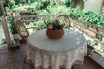Wicker basket filled with flowers on table. Basket with artificial flowers on vernada.