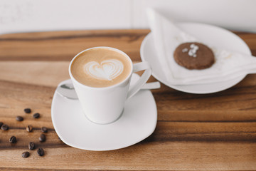 Coffee in white cup, spoon, coffee beans on wooden table