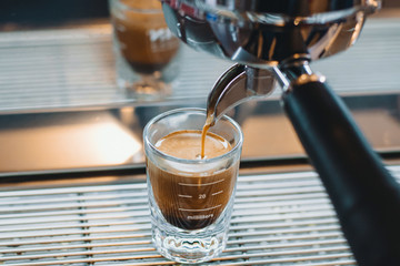 Pouring coffee in glass coffee cup, espresso machine 