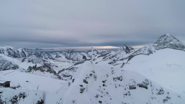 Cross on top of mountain panning round shot looking over surrounding view of the Alps
