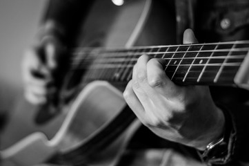 Guitar player chords close up on the strings - black and white, selective focus.