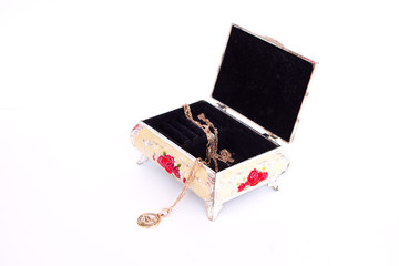 The jewelry box is open and stands on a white background. inside lies a gold chain with a pendant hanging on a gun