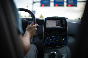 Young man driving an electric vehicle in a city context. Car sharing concept. eCar concept.