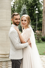 Naklejka premium Bride and groom on their wedding day, walking outdoors in spring nature. Just married, happy newlywed woman and man embracing in a green park. Loving wedding couple outdoors.