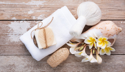 Spa wellness, exotic tropical plumeria flowers ,coconut soap,scrub,sea shells, white towels and massage herb pressure on wood background,flat lay