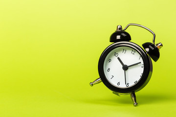 black vintage alarm clock falling to the floor with a colored background