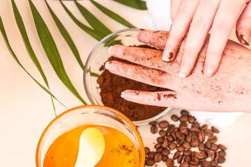 Spa care at home. Women's hands make a scrub with ground coffee. Scrub of coffee and honey. Bright background. Space for text. Horizontal photo. The view from the top.