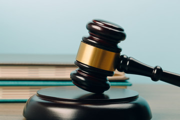 Judge Gavel with books on a wooden table and a blue background. The concept of law.