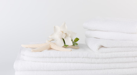 Obraz na płótnie Canvas Spa and health care concepts setup with stack of white towels star fish,Gardenia flowers on white background