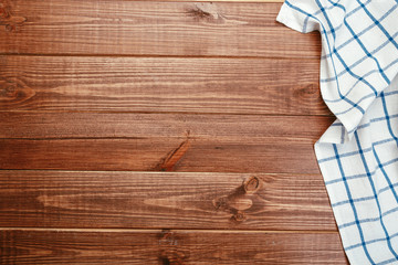 Top view on a dark wooden table with a linen kitchen towel or textile napkin. a tablecloth on a countertop made of old wood.