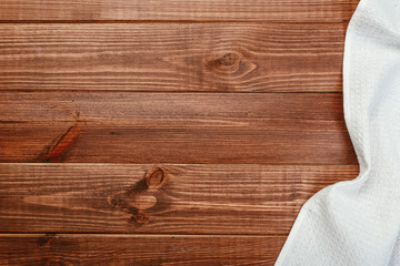 Top view on a dark wooden table with a linen kitchen towel or textile napkin. a tablecloth on a countertop made of old wood.