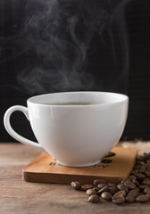 Steam hot coffee white cup on wooden plate and roasted coffee beans