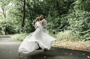 Just married couple dancing valse outdoors, free space. Bride and groom hug, blurred green grass...