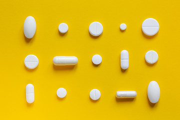 .Medical white pills on a yellow background. Pharmaceutical concept