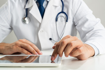 Close up of doctor hands using tablet computer