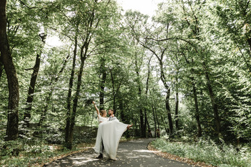 Just married couple dancing valse outdoors, free space. Bride and groom hug, blurred green grass background. The first concept of wedding dance