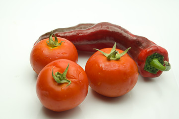 tres tomates y un pimiento rojo sobre fondo blanco