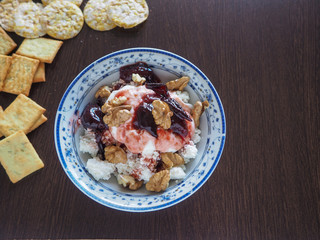 crackers around a plate with cottage cheese and a mixture of nuts and prunes on a dark surface