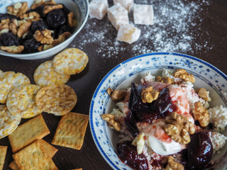 a plate of cottage cheese, nuts and jam and cereal on a dark surface for a healthy Breakfast