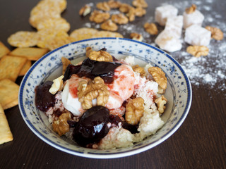 a plate of cottage cheese, nuts and jam and cereal on a dark surface for a healthy Breakfast