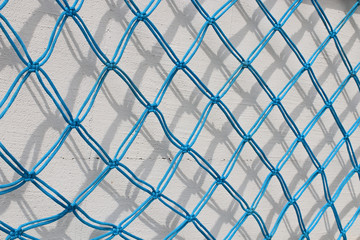 Fototapeta premium Fishnet against white wall. Handmade fishnet.