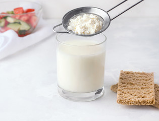 Fermented drink kefir in a glass with granules of bacteria on a white background
