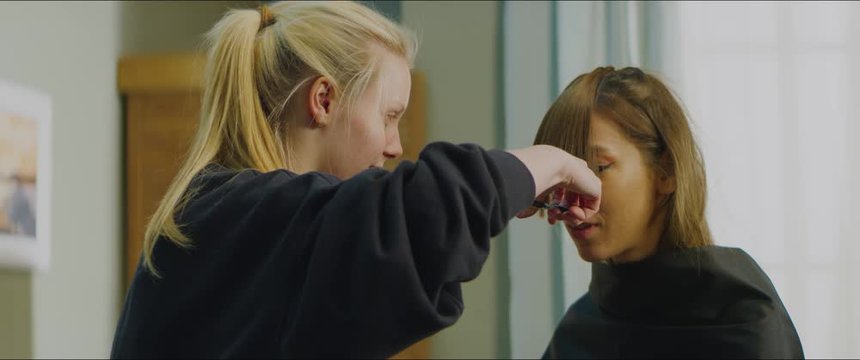 Caucasian teen girl giving a haircut to her adult sister at home. Stay home, quarantine life. Shot on RED Helium with Atlas Orion 2x Anamorphic lens
