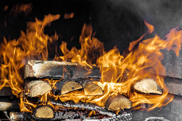 A fire is burning in a fireplace full of wood