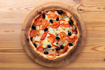 hearty italian pizza on a wooden board. .crispy cheese pizza with tomatoes, olives and mushrooms