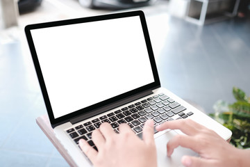 Mockup image of a woman holding blank mobile phone while using laptop with blank  screen on table in cafe.