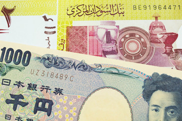 A macro image of a Japanese thousand yen note paired up with a green two pound bank note from Sudan.  Shot close up in macro.