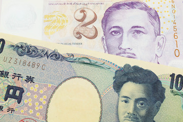 A macro image of a Japanese thousand yen note paired up with a purple and white, plastic two dollar bill from Singapore.  Shot close up in macro.