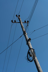 Wooden electric pole against the blue sky.