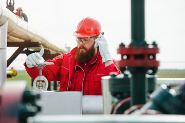 Worker at the oil field , natural gas storage in the background.