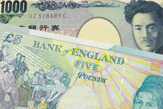 A macro image of a Japanese thousand yen note paired up with a colorful, five pound bank note from the United Kingdom.  Shot close up in macro.