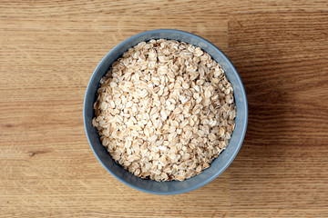 Oat flakes in bowl on wooden background.Healthy eating, vegan food concept
