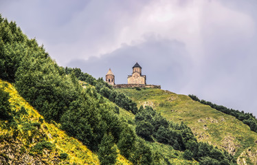 14th century Gergeti Trinity Church near the village of Gergeti in Georgia near the northern border with Russia viewed from village of Stepantsminda or Kazbegi