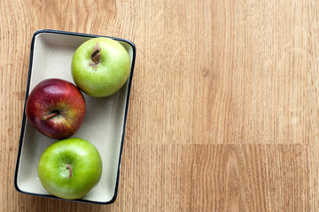 Ceramic plate in apples on wooden background.