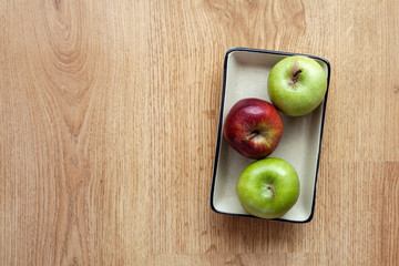 Ceramic plate in apples on wooden background.